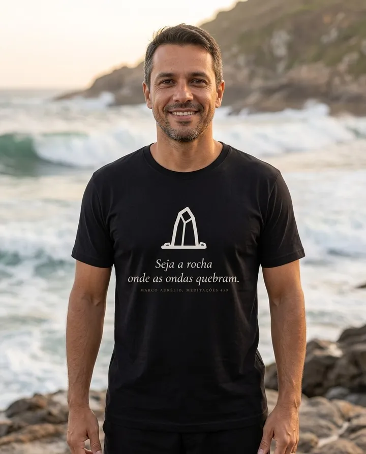 Homem vestindo a camiseta escura com a arte Seja a rocha onde as ondas quebram